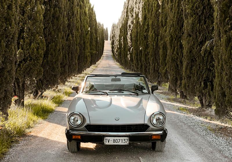 Classic convertible on a cypress-lined road in Tuscany – bespoke luxury travel with Grand Europa
